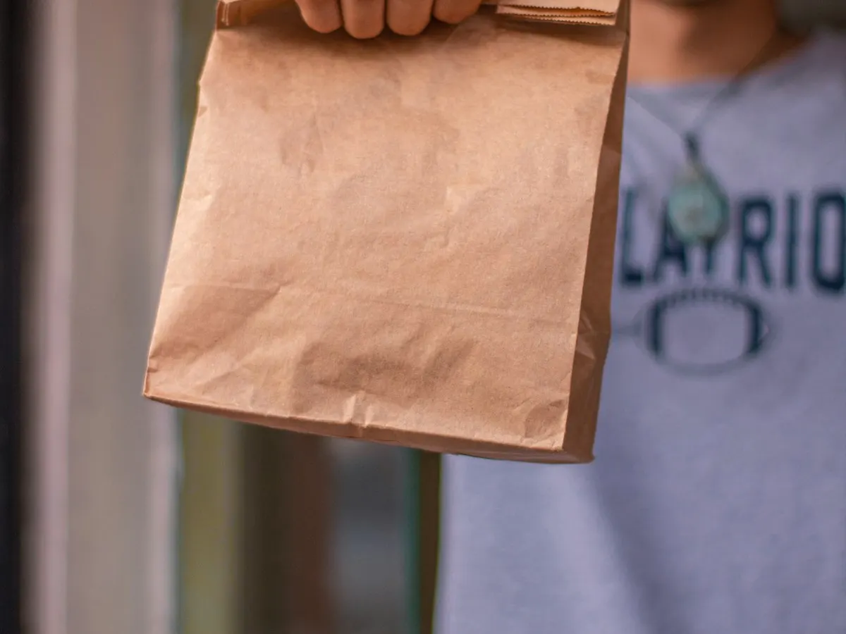 Dueño de soda empacando un rescatico en bolsas de papel