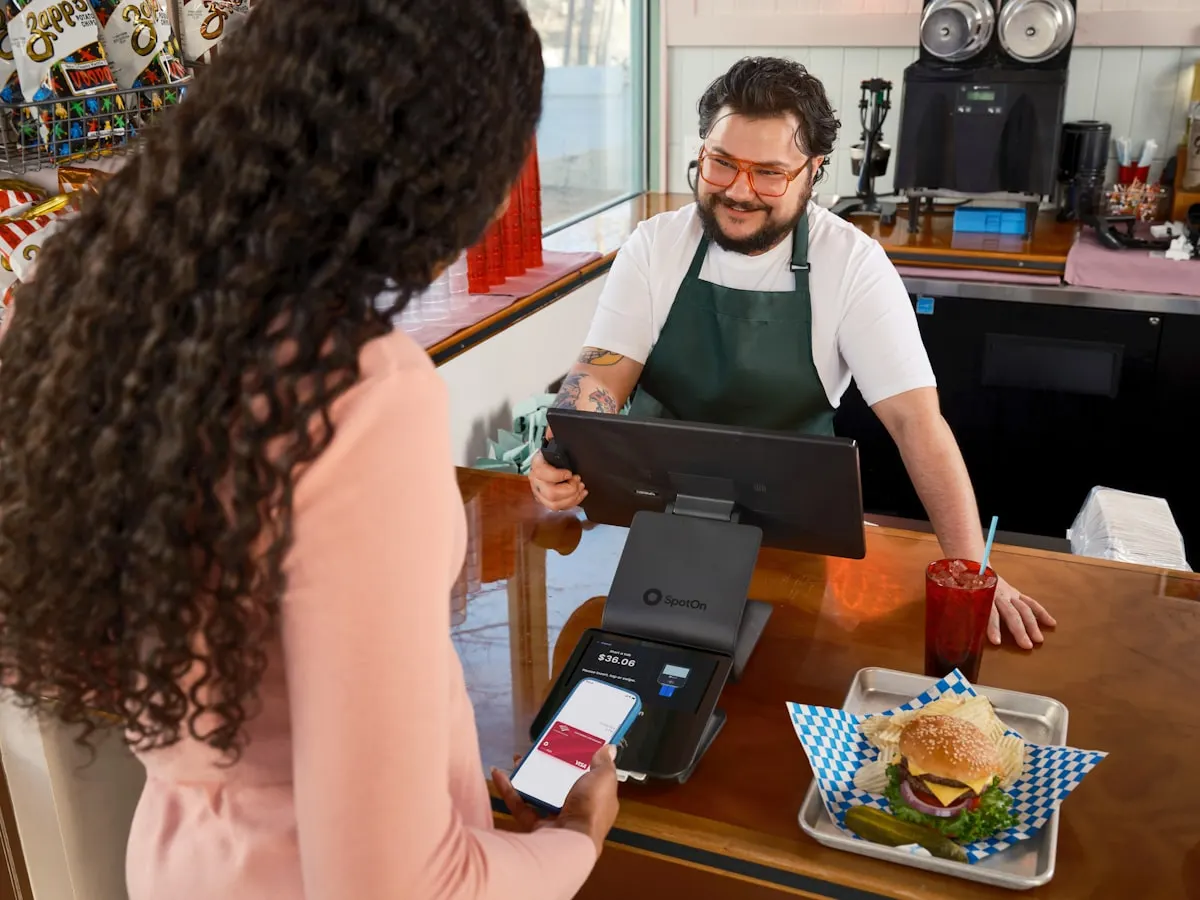 Persona revisando su celular frente al mostrador de un restaurante pequeño